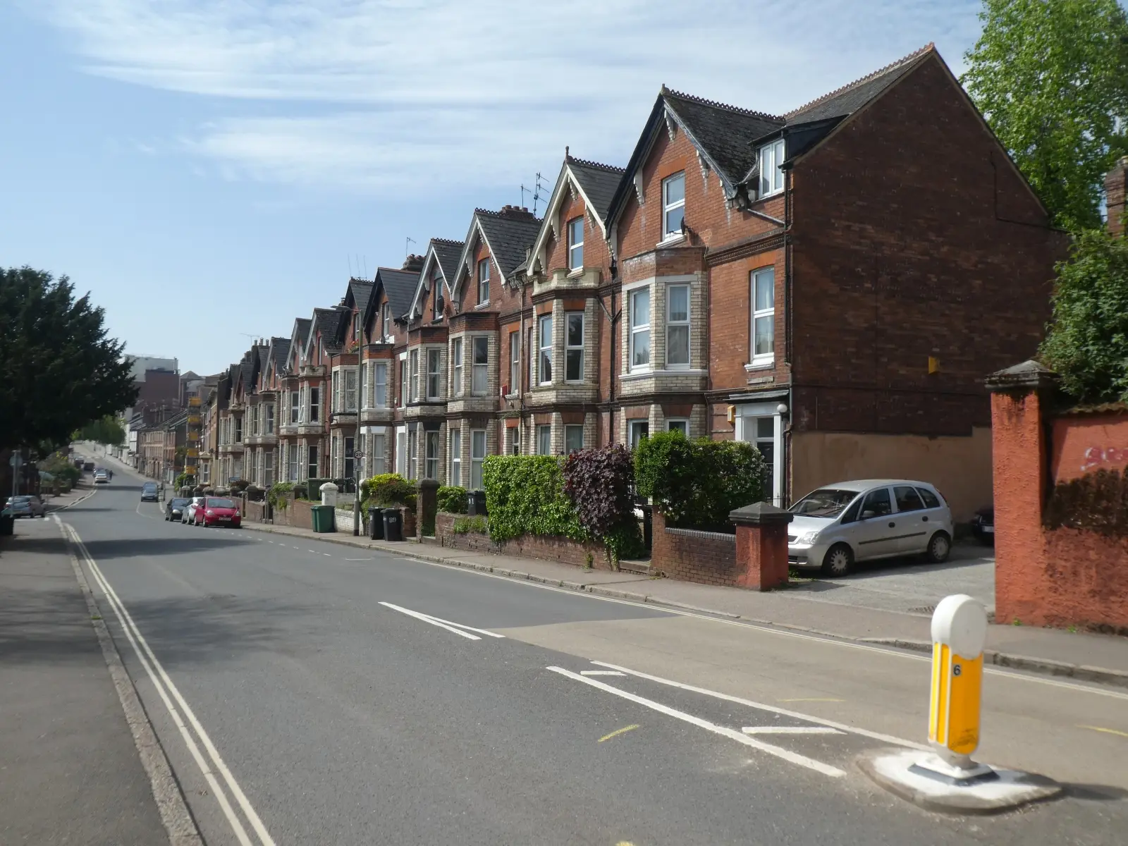 A row of Victorian red-brick houses on a tree-lined street